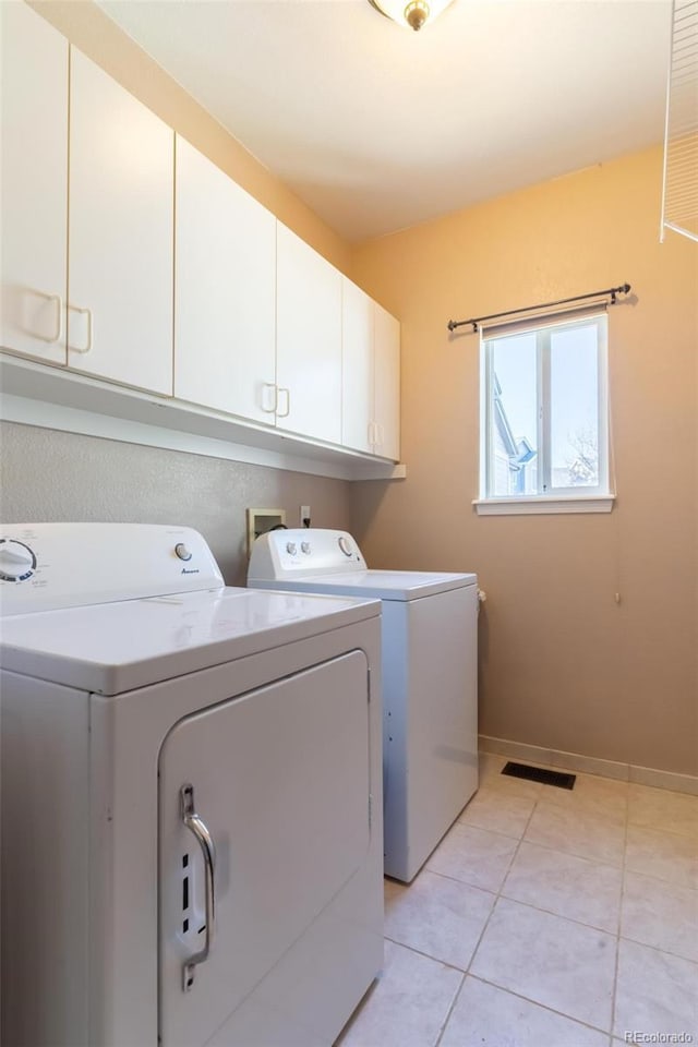 clothes washing area with cabinets, independent washer and dryer, and light tile patterned floors