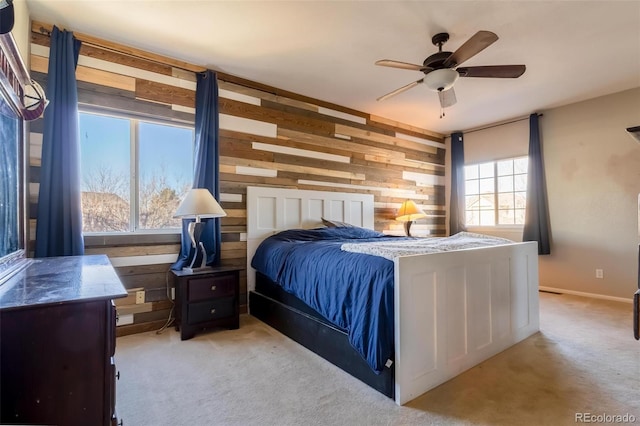 bedroom featuring ceiling fan, wood walls, and light colored carpet