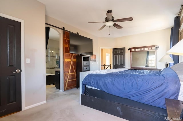 bedroom with ceiling fan, a barn door, light carpet, and connected bathroom