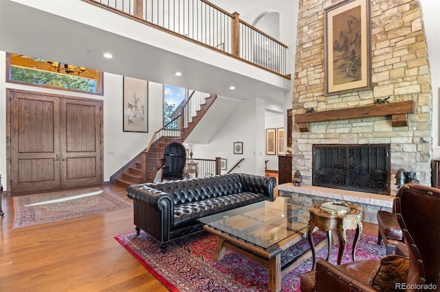 living room with hardwood / wood-style flooring, a towering ceiling, and a fireplace