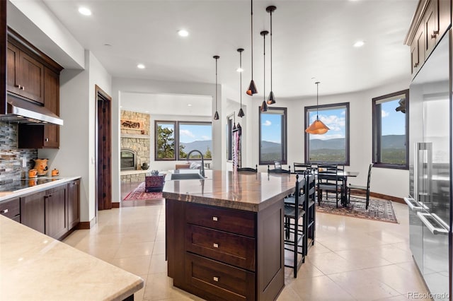 kitchen with sink, pendant lighting, black electric stovetop, a large island, and range hood