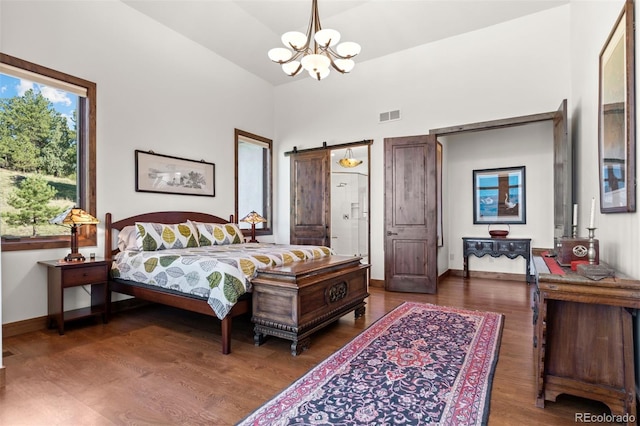 bedroom featuring dark hardwood / wood-style flooring, a notable chandelier, lofted ceiling, and a barn door