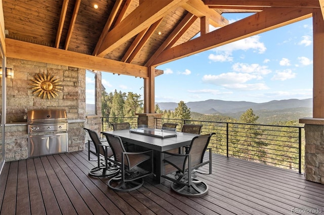 deck with exterior kitchen, area for grilling, a fireplace, and a mountain view