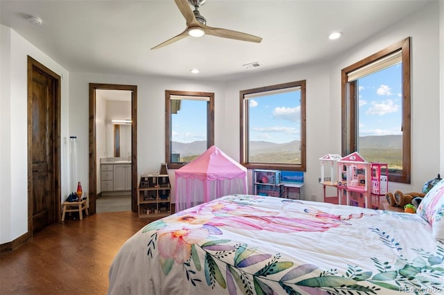 bedroom with ceiling fan, a mountain view, dark wood-type flooring, and ensuite bath