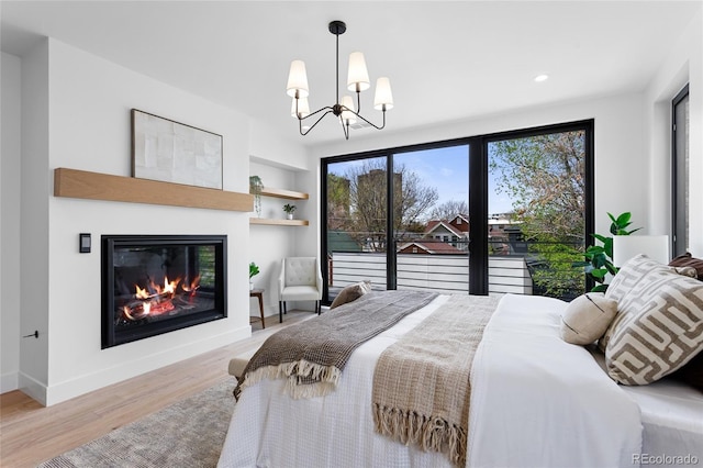 357 S Franklin St, Denver, CO 80209 - bedroom featuring wood finished floors, a chandelier, recessed lighting, baseboards, and a glass covered fireplace