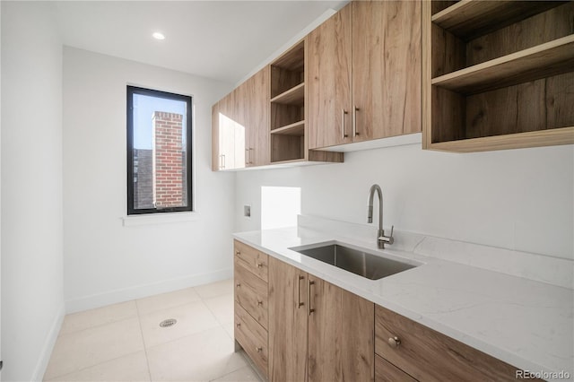 357 S Franklin St, Denver, CO 80209 - kitchen with open shelves, a sink, baseboards, light stone countertops, and light tile patterned floors