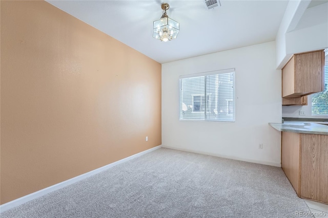 unfurnished dining area featuring a notable chandelier and light colored carpet