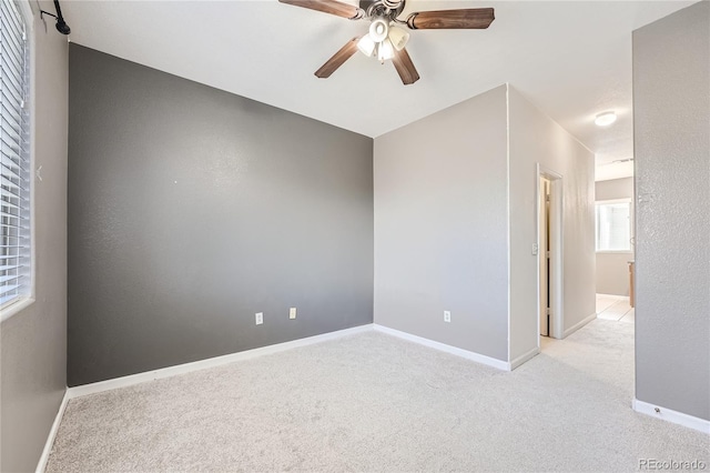 spare room with ceiling fan and light colored carpet