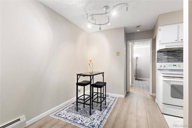 dining room featuring light wood-type flooring, a textured ceiling, and a baseboard heating unit