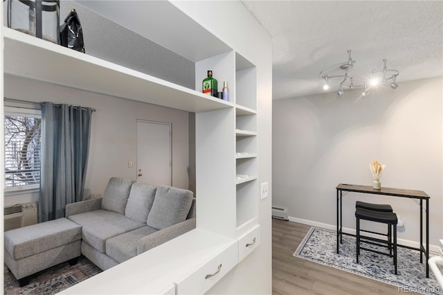 living room with hardwood / wood-style flooring, baseboard heating, and a textured ceiling