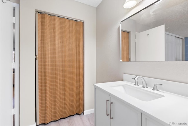 bathroom with vanity, wood-type flooring, and a textured ceiling