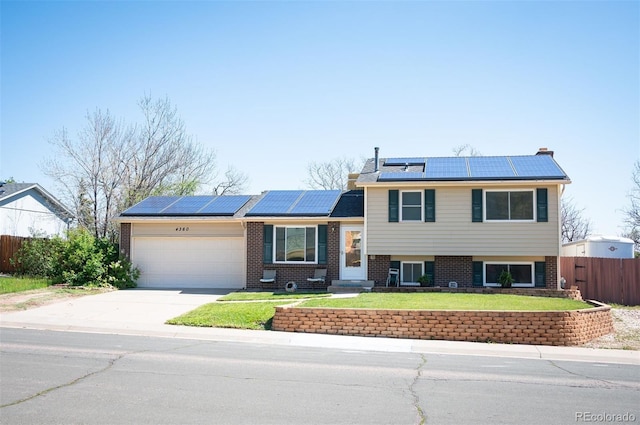 split level home with an attached garage, brick siding, concrete driveway, and roof mounted solar panels