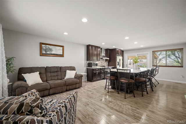 living area with recessed lighting, light wood-style floors, and baseboards