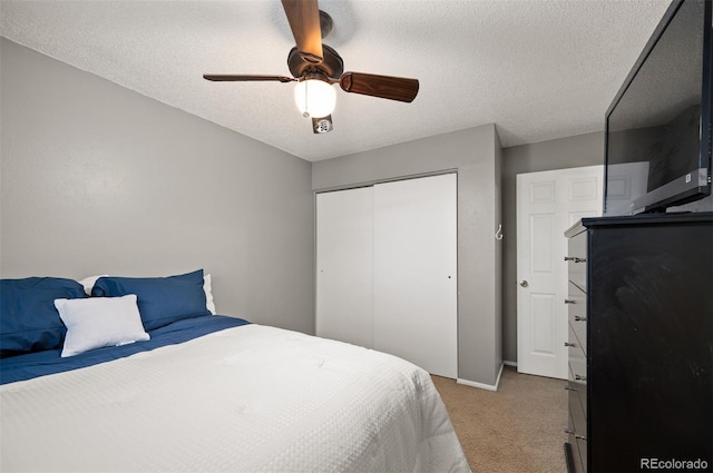 bedroom featuring light carpet, a closet, a ceiling fan, a textured ceiling, and baseboards