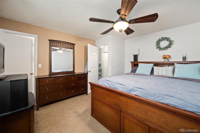 bedroom featuring light carpet, a textured ceiling, and a ceiling fan