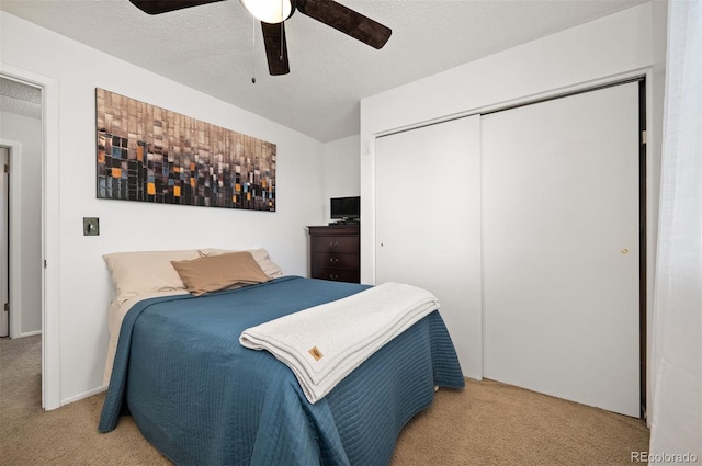carpeted bedroom featuring a closet, a textured ceiling, and ceiling fan