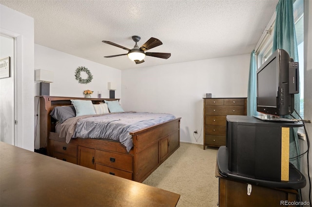 bedroom featuring light carpet, ceiling fan, and a textured ceiling