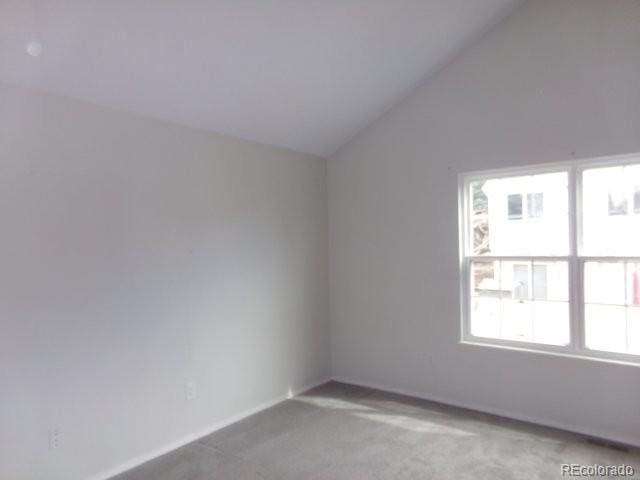 spare room featuring light carpet and vaulted ceiling