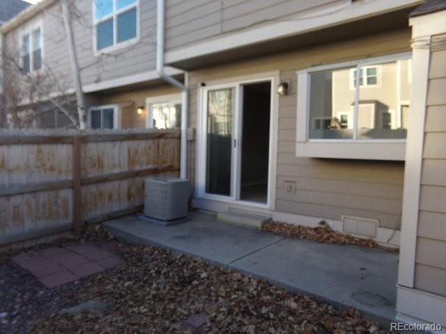 back of house with central AC unit and fence