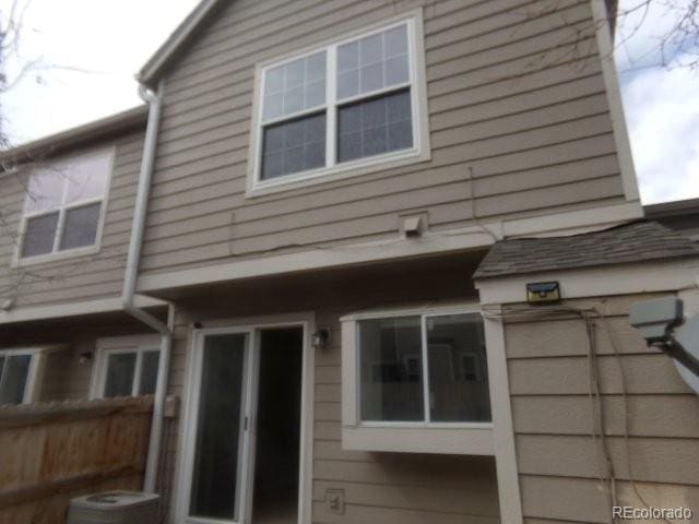 rear view of house with fence and central AC