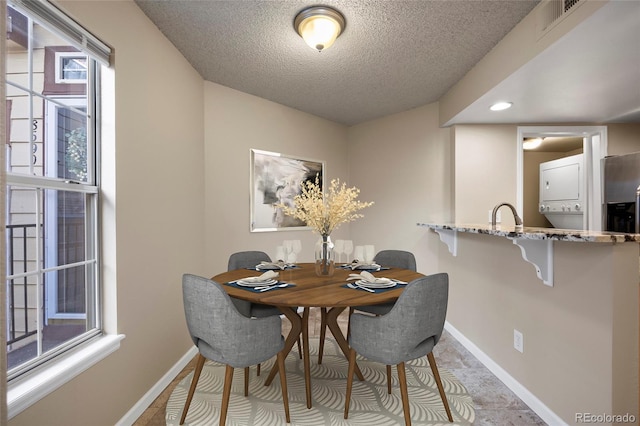 dining room featuring a textured ceiling and stacked washer / dryer