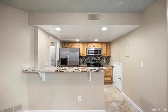 kitchen featuring tasteful backsplash, appliances with stainless steel finishes, a kitchen breakfast bar, and light tile patterned flooring