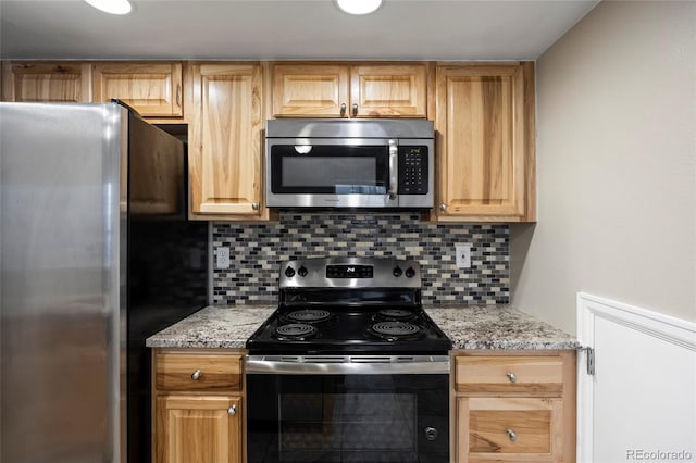 kitchen featuring stainless steel appliances, decorative backsplash, and light stone counters