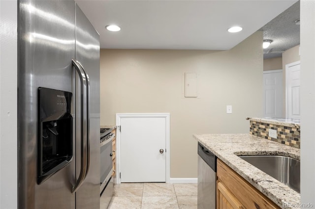 kitchen featuring stainless steel appliances, sink, backsplash, light stone counters, and light tile patterned floors