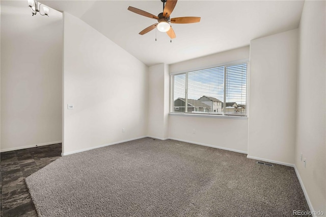 empty room featuring vaulted ceiling, ceiling fan with notable chandelier, and dark carpet