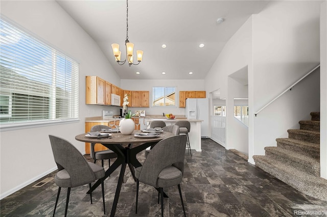 dining space featuring a healthy amount of sunlight, vaulted ceiling, and a notable chandelier