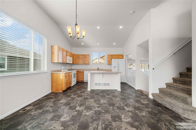 kitchen featuring white appliances, hanging light fixtures, a wealth of natural light, and a kitchen island