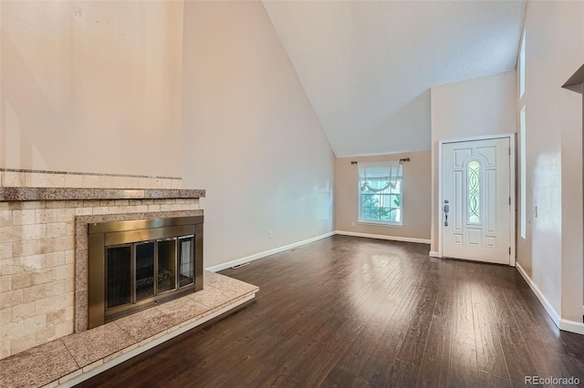 unfurnished living room featuring high vaulted ceiling and dark hardwood / wood-style flooring