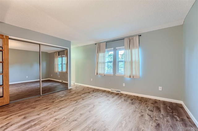 unfurnished bedroom with a closet, hardwood / wood-style flooring, and a textured ceiling