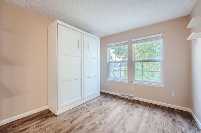 unfurnished bedroom featuring a closet, a textured ceiling, and light hardwood / wood-style floors