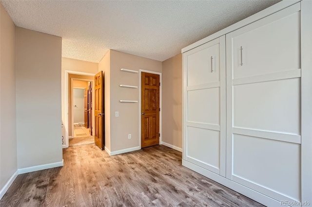 unfurnished bedroom with a closet, a textured ceiling, and light wood-type flooring