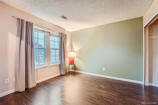 spare room with dark wood-type flooring and a textured ceiling