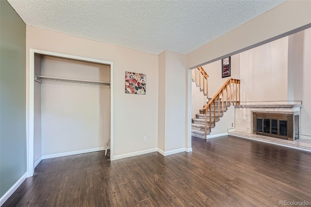 unfurnished living room featuring dark wood-type flooring and a textured ceiling