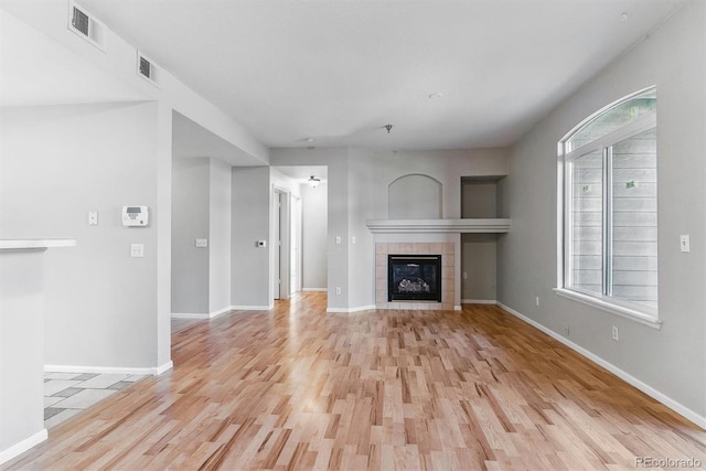 unfurnished living room with baseboards, visible vents, light wood-style flooring, and a fireplace