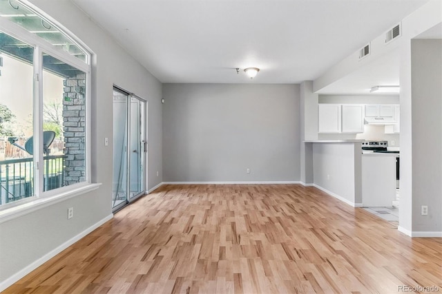 unfurnished living room featuring visible vents, plenty of natural light, and light wood-style flooring