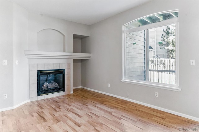 unfurnished living room featuring baseboards, wood finished floors, and a tile fireplace