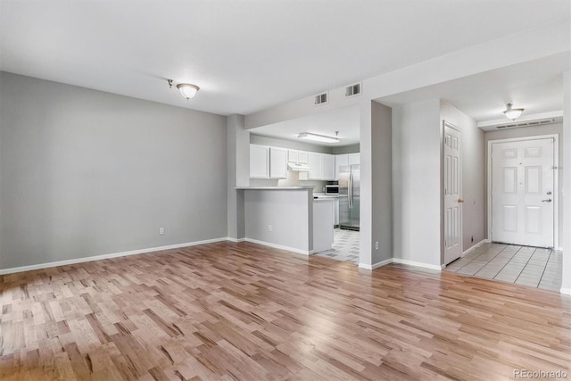 unfurnished living room with baseboards, visible vents, and light wood-type flooring