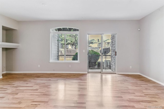 unfurnished living room featuring light wood-style floors, baseboards, and a fireplace