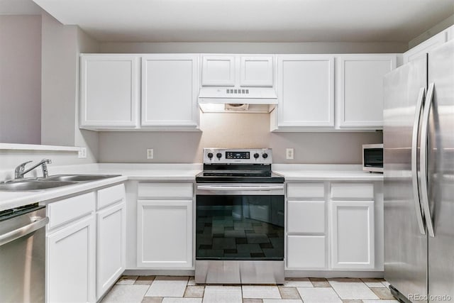 kitchen with under cabinet range hood, stainless steel appliances, a sink, and light countertops