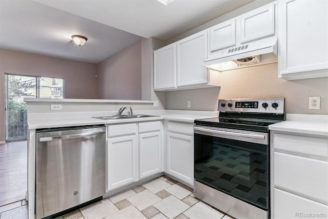 kitchen with a peninsula, light countertops, under cabinet range hood, a sink, and appliances with stainless steel finishes