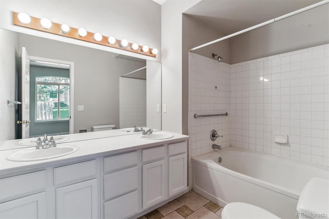 bathroom featuring a sink, toilet, double vanity, and shower / washtub combination