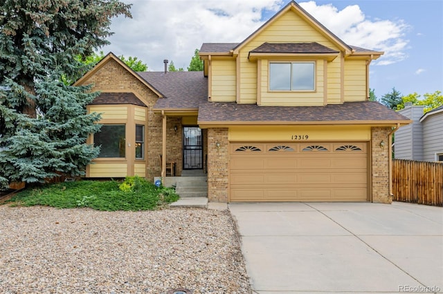 12319 W Burgundy Ave, Littleton, CO 80127 - view of front facade featuring brick siding, an attached garage, driveway, and a shingled roof