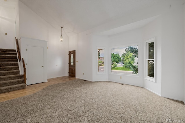 12319 W Burgundy Ave, Littleton, CO 80127 - unfurnished living room with carpet floors, a towering ceiling, and stairway