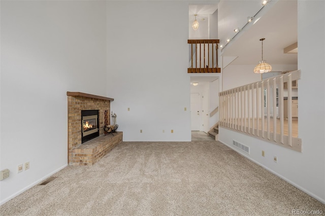 12319 W Burgundy Ave, Littleton, CO 80127 - unfurnished living room featuring a towering ceiling, carpet, a brick fireplace, stairs, and track lighting