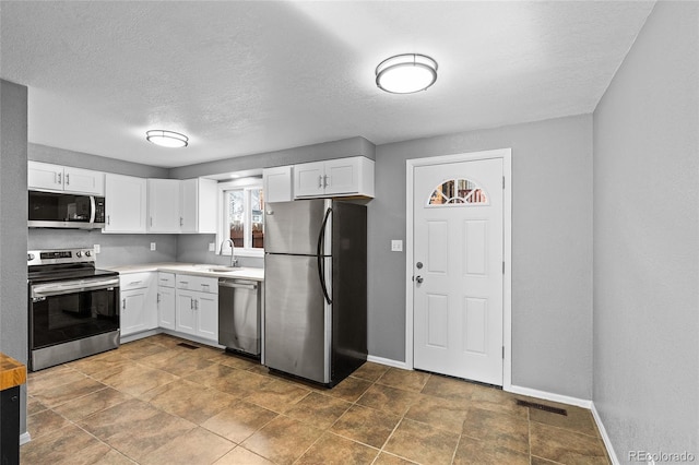 kitchen featuring white cabinetry, sink, stainless steel appliances, and a textured ceiling