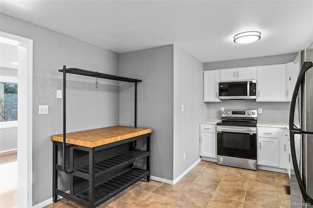 kitchen featuring appliances with stainless steel finishes, a textured ceiling, and white cabinets